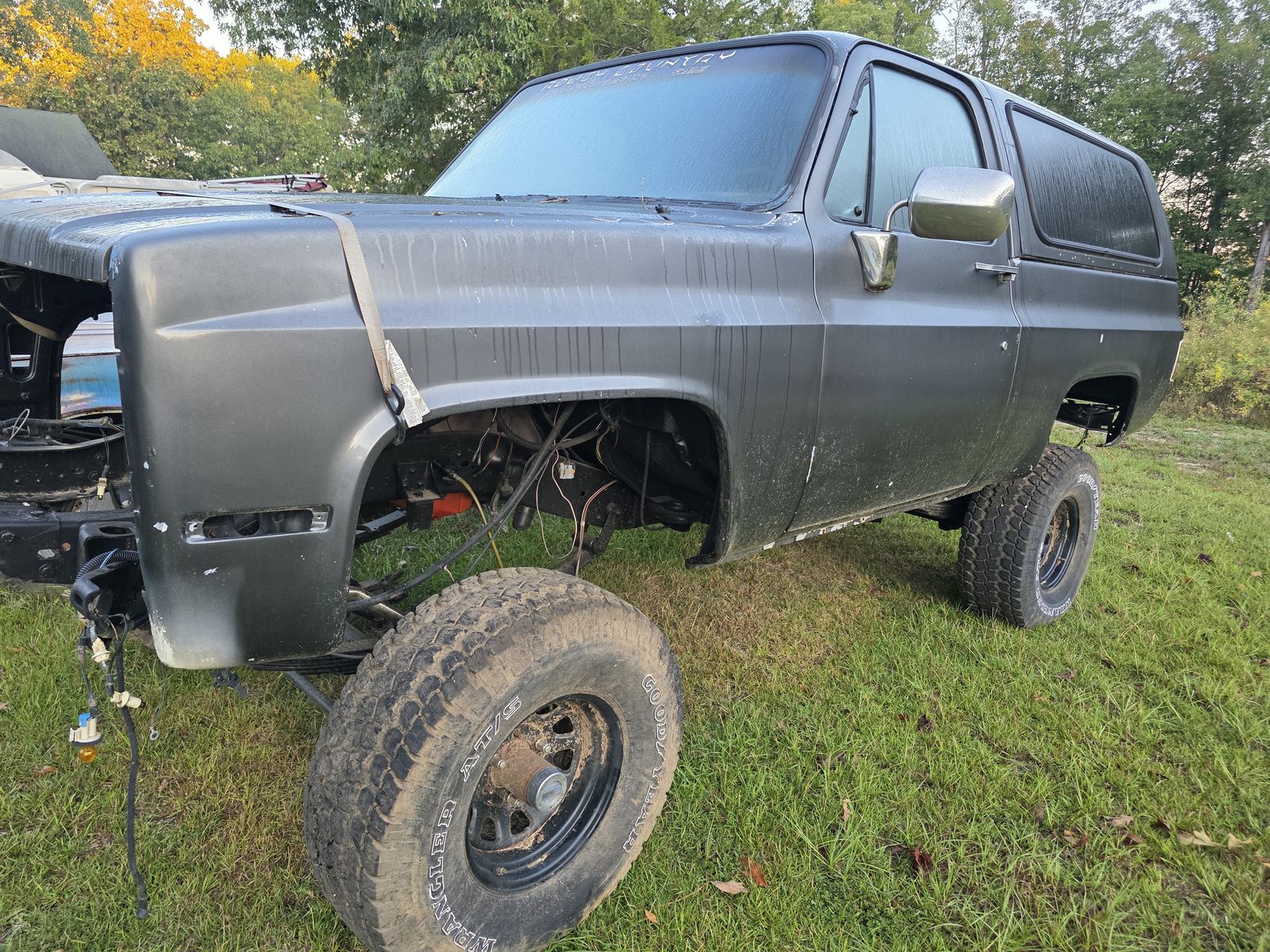 Lifted gray Chevrolet K5 Blazer with the front end removed and wiring exposed