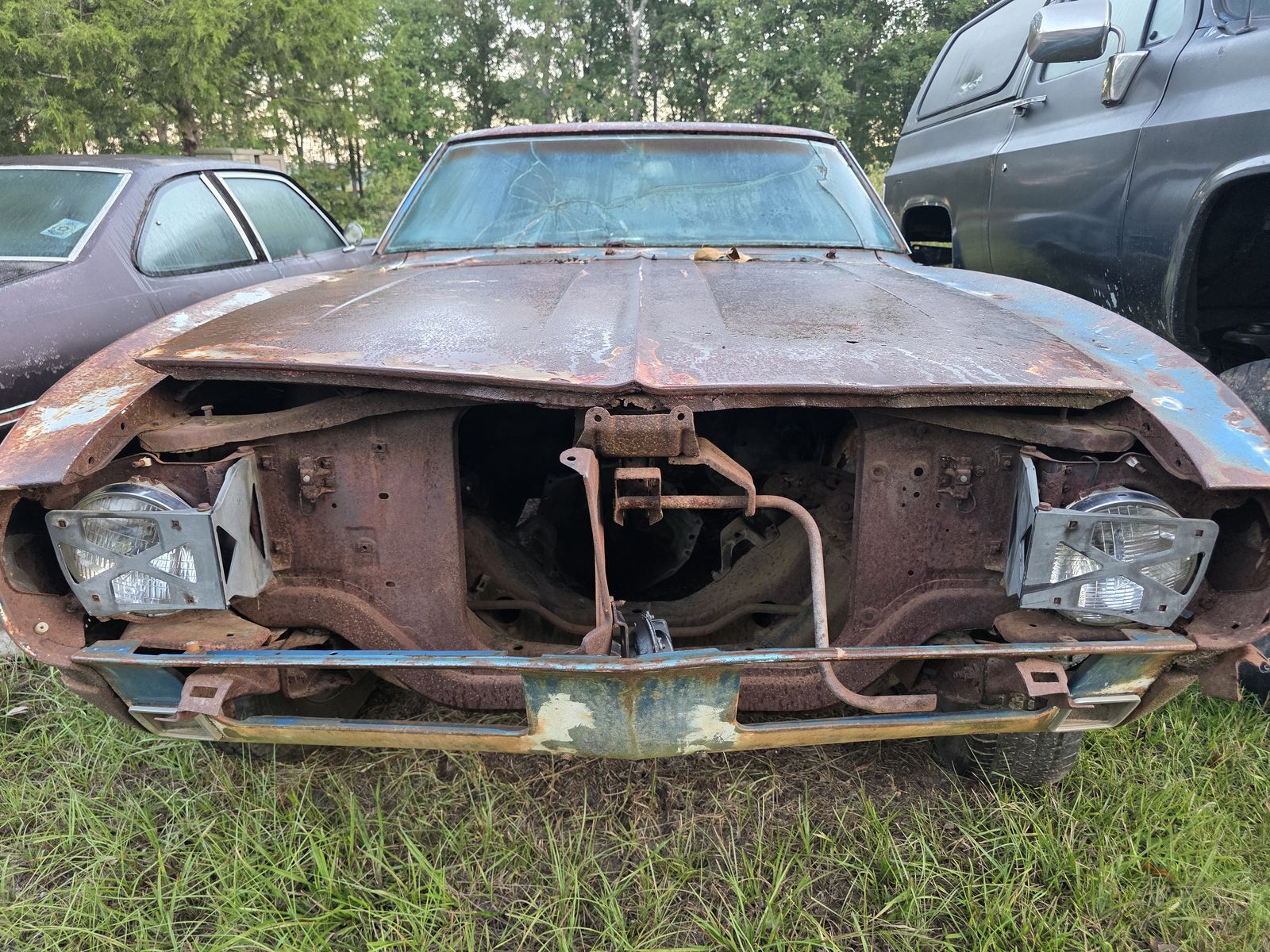 Front of the Camaro SS with a rusted hood and the nose disassembled down to the core support