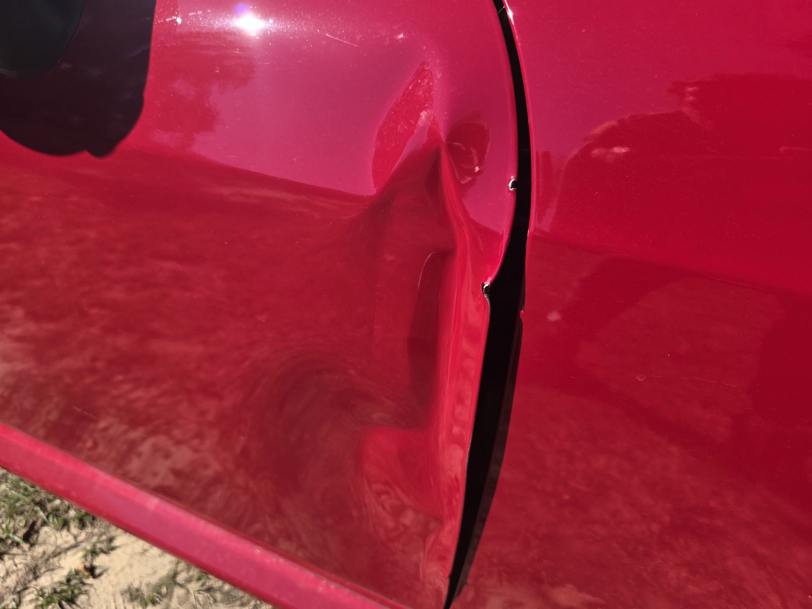 Close-up of a creased red door skin at the rear edge